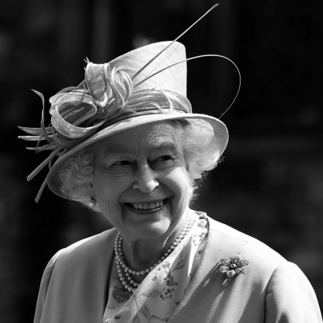 Black and white photograph of the Queen smiling, looking away from the right of the camera